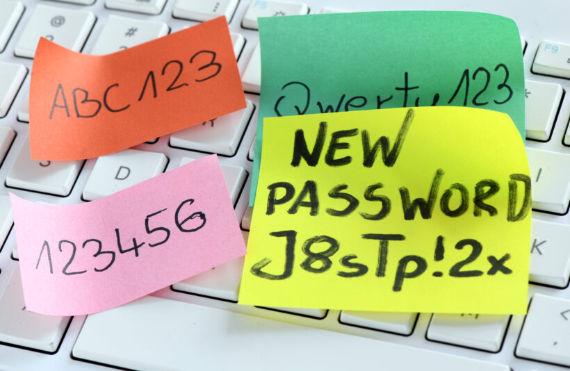 Sticky notes with various passwords are placed on a white keyboard. The green note says "new password j8stp! 2x," the orange note says "abc123," the pink note says "123456," and the light green note says "qwerty123. " to ensure password security, always create strong passwords.